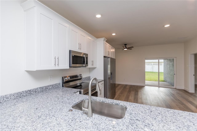 kitchen with light stone counters, white cabinetry, appliances with stainless steel finishes, dark hardwood / wood-style floors, and sink