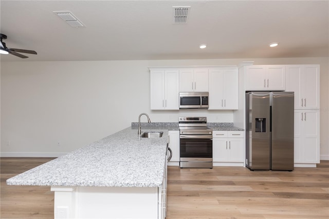 kitchen with stainless steel appliances, white cabinets, sink, and light wood-type flooring