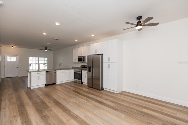 kitchen featuring light wood-type flooring, appliances with stainless steel finishes, sink, white cabinets, and kitchen peninsula