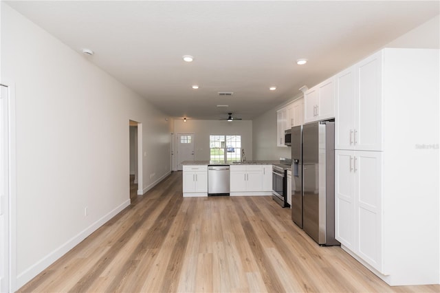 kitchen with stainless steel appliances, sink, kitchen peninsula, white cabinets, and light wood-type flooring