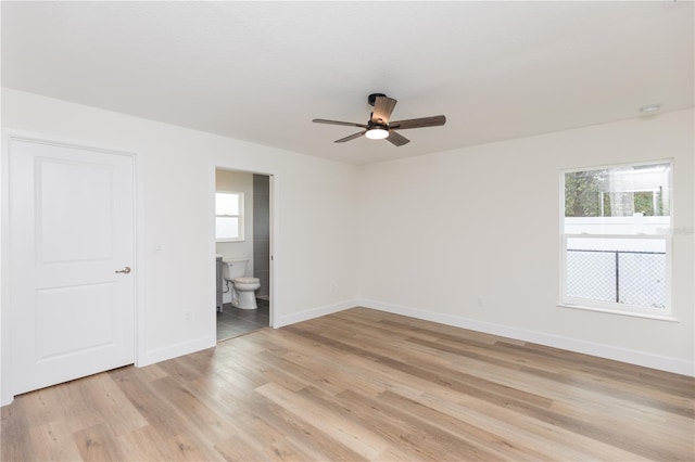 unfurnished bedroom with light hardwood / wood-style floors, multiple windows, ceiling fan, and connected bathroom