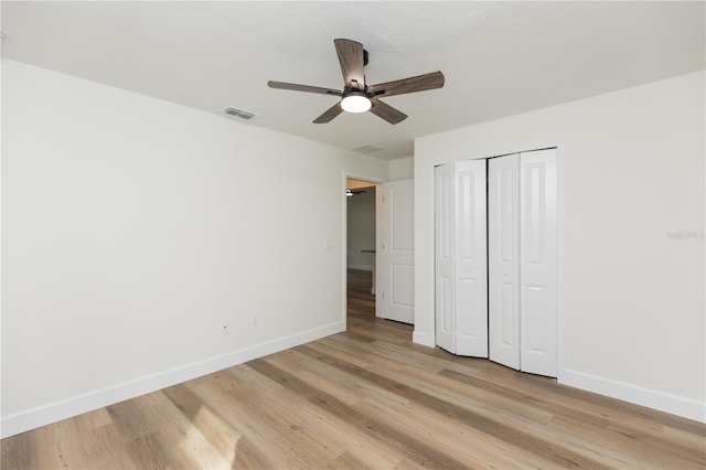 unfurnished bedroom featuring light hardwood / wood-style flooring, ceiling fan, and a closet