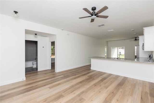 unfurnished living room featuring ceiling fan, sink, and light hardwood / wood-style flooring