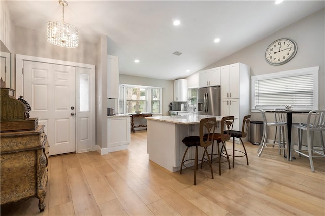 kitchen featuring a kitchen island, white cabinets, light hardwood / wood-style flooring, vaulted ceiling, and stainless steel refrigerator with ice dispenser