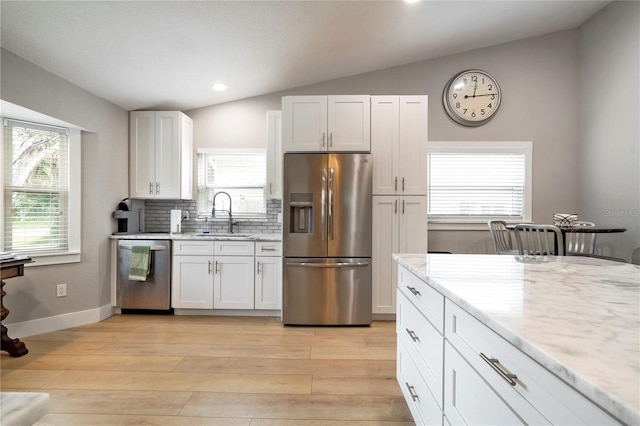 kitchen featuring stainless steel appliances, white cabinetry, lofted ceiling, light wood-type flooring, and sink