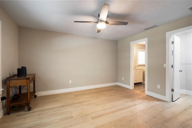 bedroom featuring ensuite bathroom, a textured ceiling, ceiling fan, and light wood-type flooring