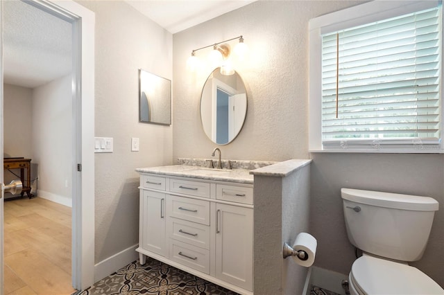 bathroom featuring toilet, large vanity, plenty of natural light, and tile flooring