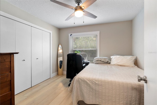 bedroom featuring a closet, a textured ceiling, light hardwood / wood-style floors, and ceiling fan