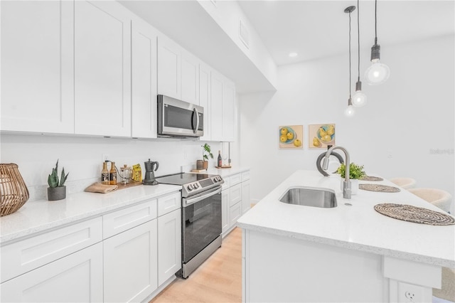 kitchen featuring pendant lighting, sink, white cabinetry, appliances with stainless steel finishes, and light hardwood / wood-style floors