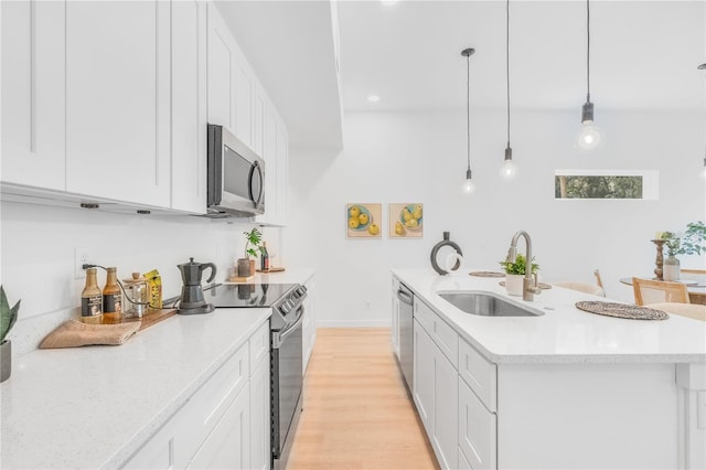 kitchen featuring white cabinets, appliances with stainless steel finishes, decorative light fixtures, and sink