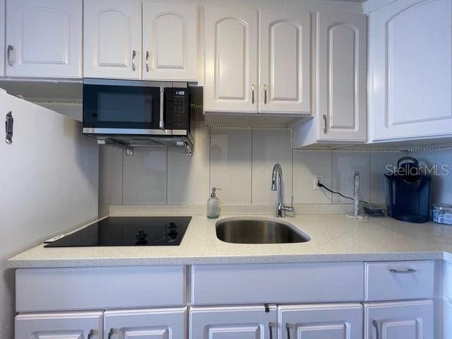 kitchen with black electric cooktop, sink, and white cabinets