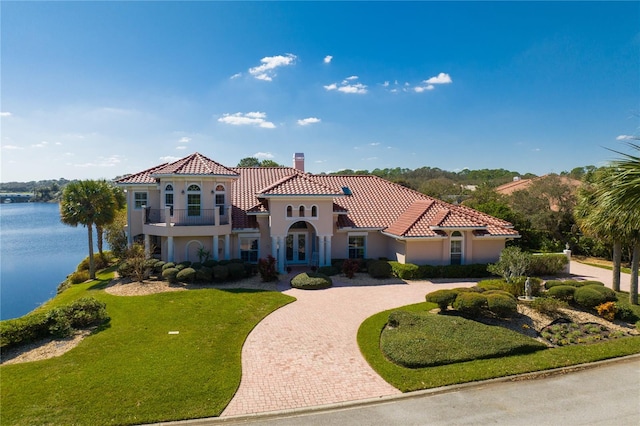 mediterranean / spanish-style house featuring a front yard and a water view