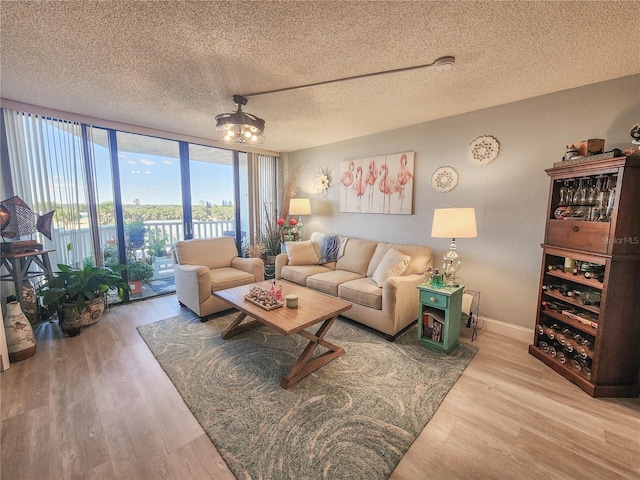 living room featuring a textured ceiling, light hardwood / wood-style floors, and floor to ceiling windows