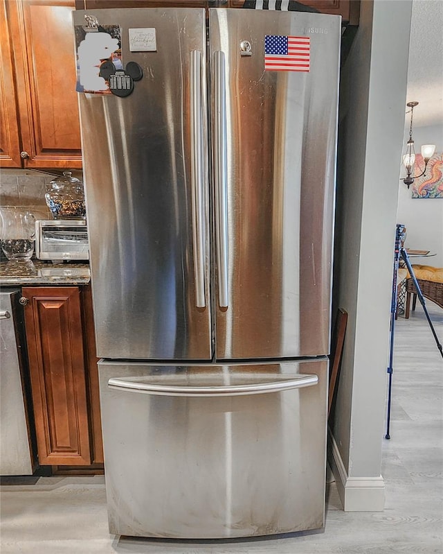 details featuring backsplash, stainless steel fridge, light wood-type flooring, a chandelier, and dishwasher