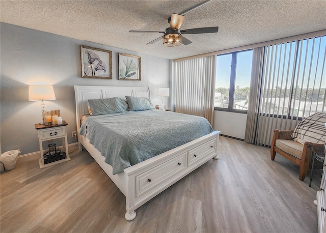 bedroom featuring light hardwood / wood-style floors, ceiling fan, and a textured ceiling