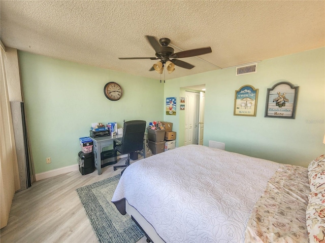 bedroom featuring a textured ceiling, ceiling fan, and light wood-type flooring