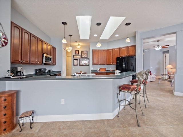 kitchen with a skylight, pendant lighting, stove, and ceiling fan