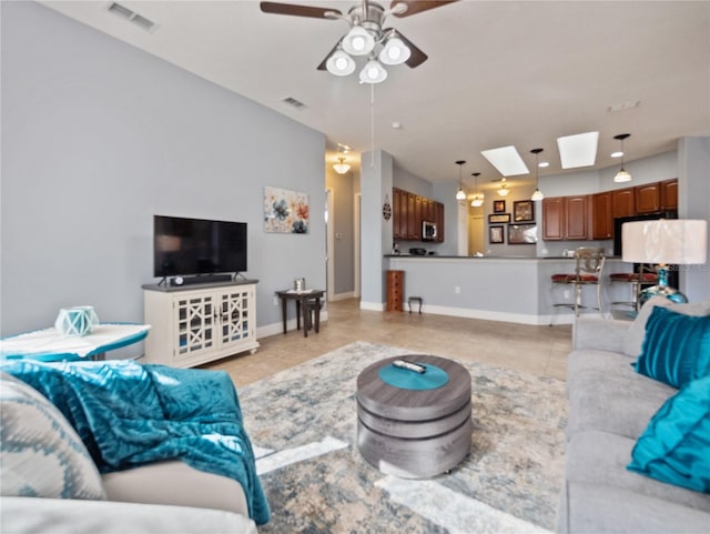 living room with light tile floors, ceiling fan, and a skylight