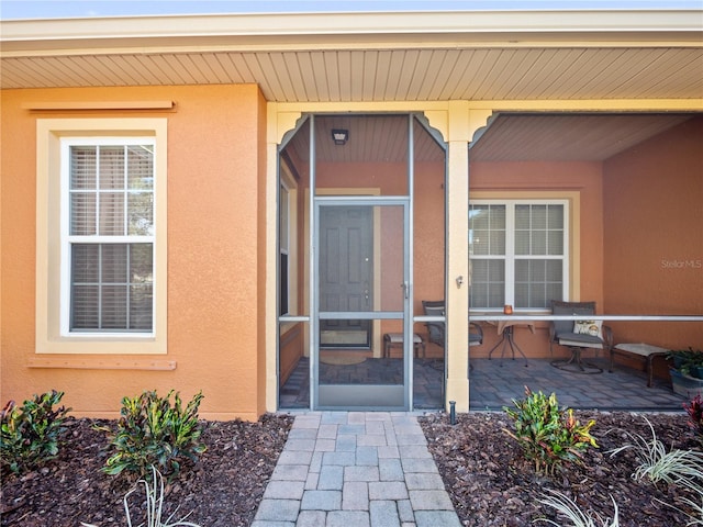 doorway to property featuring a patio area and stucco siding