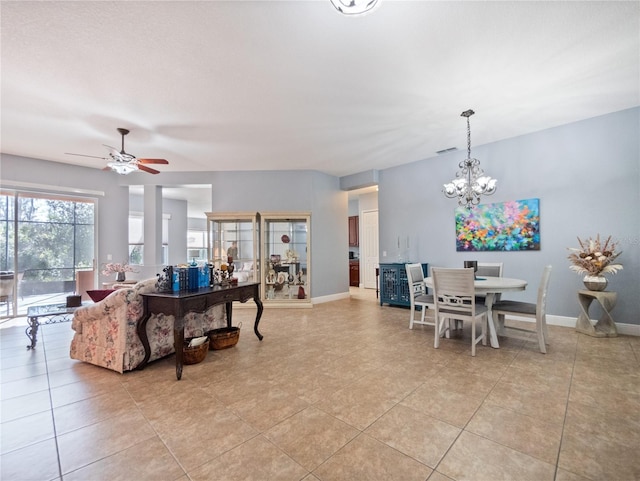 living area featuring light tile patterned floors, baseboards, and ceiling fan with notable chandelier