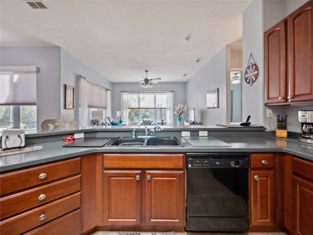 kitchen featuring visible vents, dishwasher, dark countertops, brown cabinets, and a sink