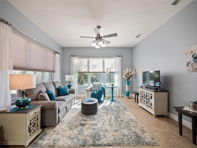 living room featuring light tile patterned floors, ceiling fan, visible vents, and a textured ceiling