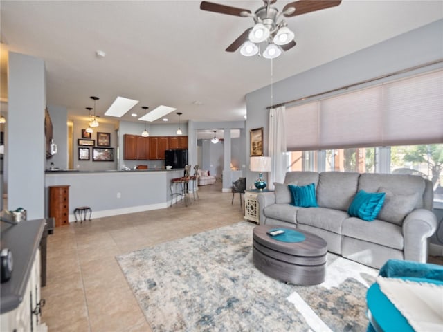 living room featuring light tile patterned floors, a skylight, baseboards, ceiling fan, and recessed lighting