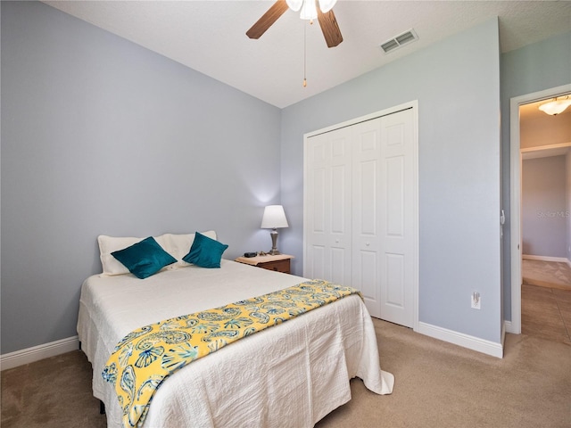 carpeted bedroom with a ceiling fan, a closet, visible vents, and baseboards