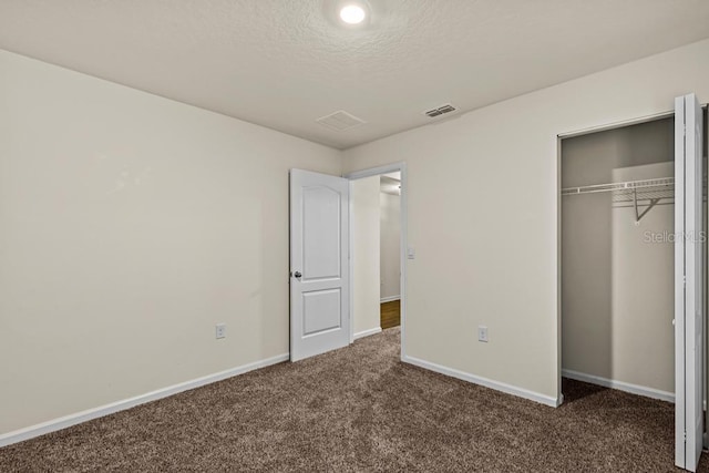 unfurnished bedroom featuring dark carpet and a closet