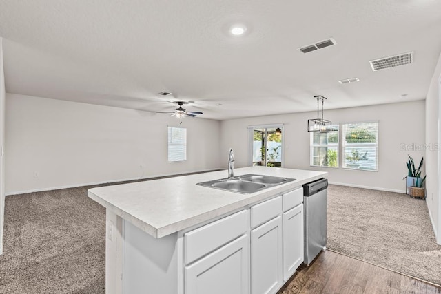 kitchen with ceiling fan with notable chandelier, dark carpet, a center island with sink, dishwasher, and sink