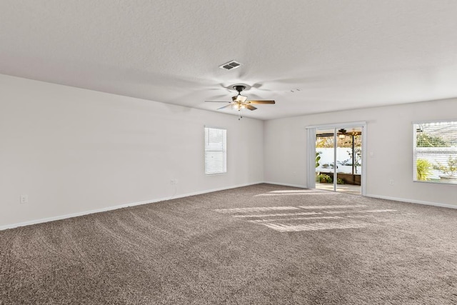 spare room featuring dark colored carpet and ceiling fan