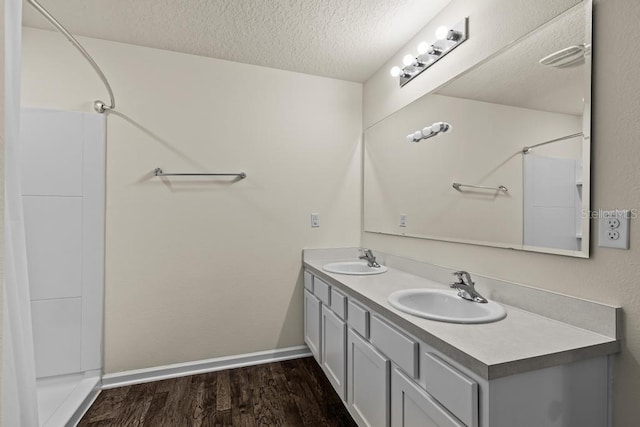 bathroom featuring a textured ceiling, wood-type flooring, and dual vanity