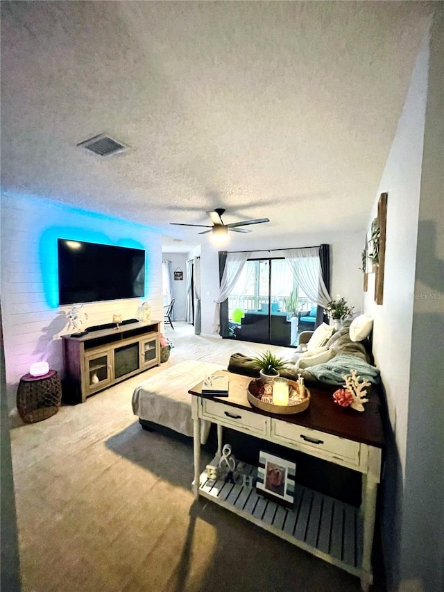 living room with ceiling fan, carpet floors, and a textured ceiling