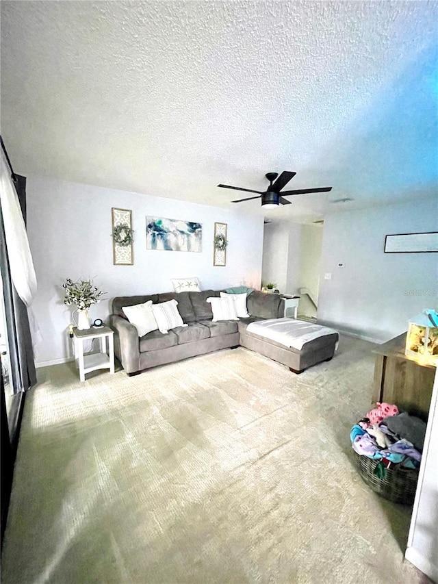 living room featuring carpet floors, ceiling fan, and a textured ceiling