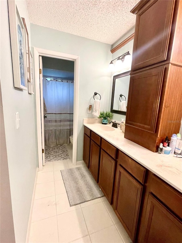 bathroom with a textured ceiling, tile patterned flooring, vanity, and toilet