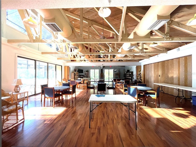 recreation room featuring a healthy amount of sunlight, vaulted ceiling, visible vents, and wood finished floors