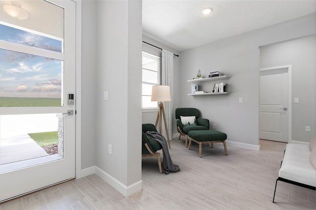 living area featuring baseboards and light wood-type flooring