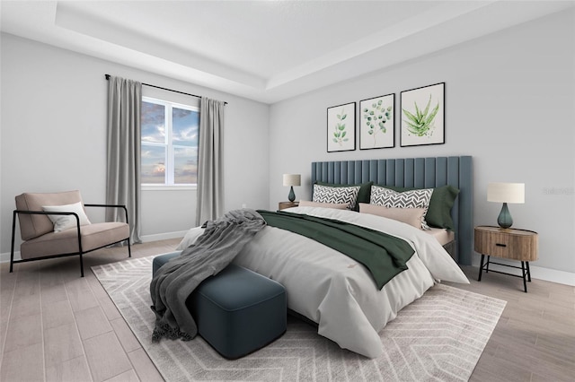 bedroom with baseboards, a raised ceiling, and wood finished floors