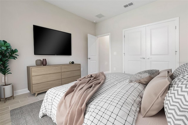 bedroom featuring baseboards, visible vents, a closet, and wood finish floors