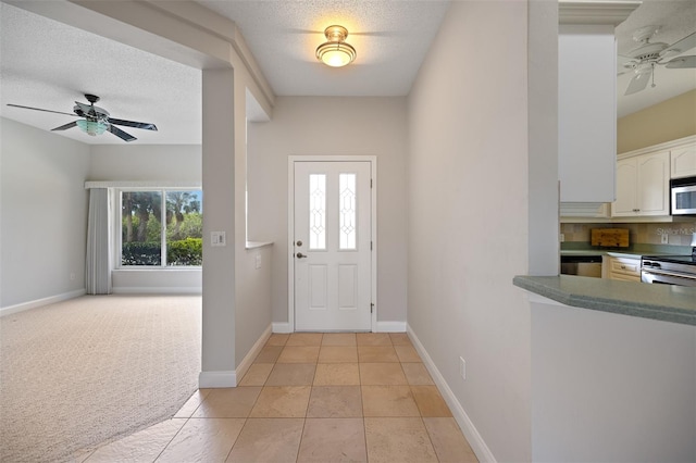 foyer entrance featuring a textured ceiling, ceiling fan, and light tile floors