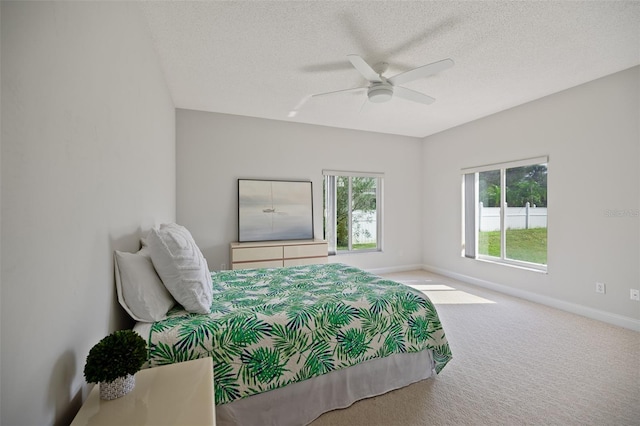 bedroom featuring light colored carpet, ceiling fan, and a textured ceiling