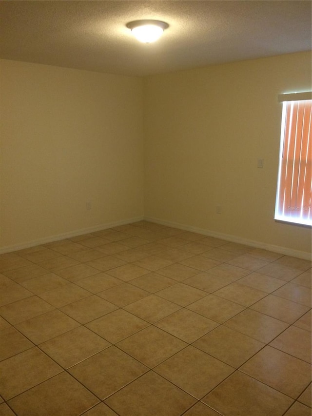 tiled empty room featuring a textured ceiling