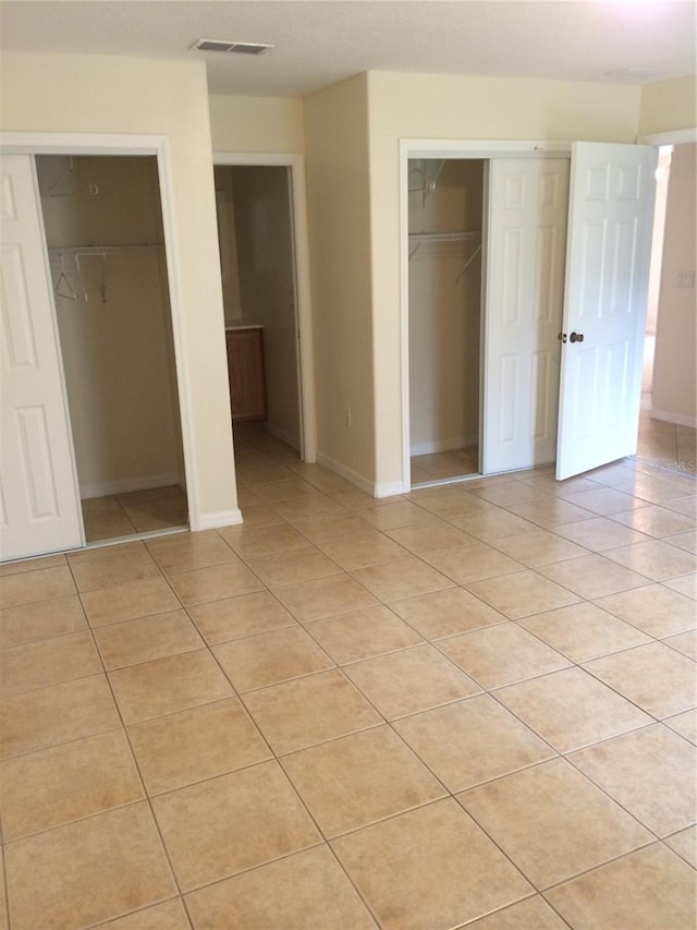 unfurnished bedroom featuring two closets and light tile floors