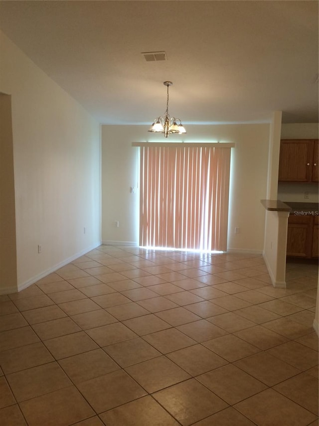 empty room featuring light tile floors and a chandelier