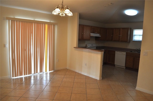 kitchen featuring decorative light fixtures, light tile flooring, sink, white dishwasher, and a chandelier