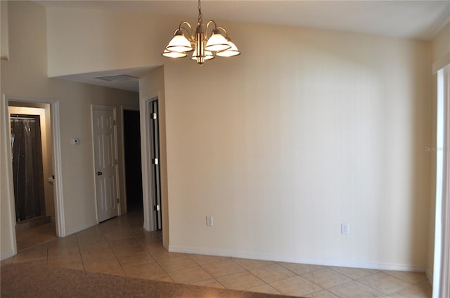 spare room featuring light tile floors and an inviting chandelier