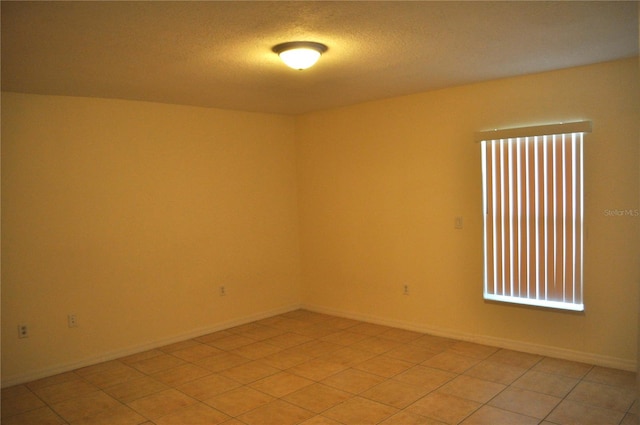 tiled spare room with a textured ceiling and a wealth of natural light