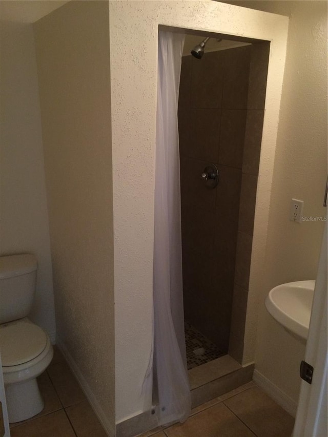 bathroom featuring toilet, tile floors, walk in shower, and sink