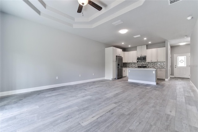 kitchen with light wood-type flooring, ceiling fan, a kitchen island, and appliances with stainless steel finishes