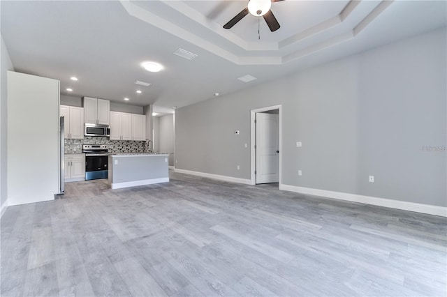 kitchen featuring white cabinetry, backsplash, light wood-type flooring, and stainless steel appliances